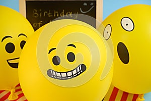 Yellow emoji balloons on the background of the board with the event inscription and American flags.