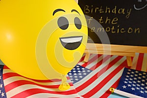 Yellow emoji balloons on the background of the board with the event inscription and American flags.