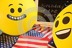 Yellow emoji balloons on the background of the board with the event inscription and American flags.