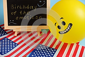 Yellow emoji balloons on the background of the board with the event inscription and American flags.