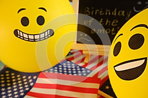 Yellow emoji balloons on the background of the board with the event inscription and American flags.