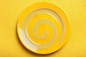 Yellow empty plate over yellow background