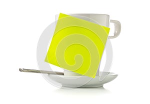Yellow empty sticky note on white coffee or tea cup over white background