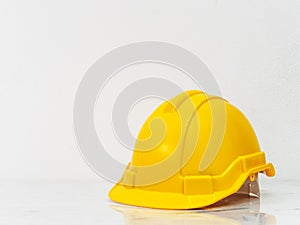 Yellow engineer safety hat put on white marble counter top with