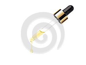 Yellow essential serum oil dripping from gold dropper