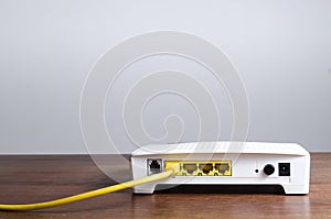 Yellow ethernet cable connected to modem router port on a wooden table