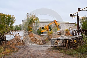 Yellow excavator breaks an old brick building.