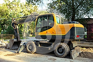 Yellow excavator with bucket lowered into the ground