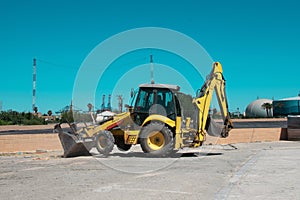 yellow excavator bulldozer on concrete surface against blue sky.
