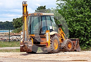 Yellow excavator, bulldozer machine and worker tractor. Road works. Road machinery at construction site.