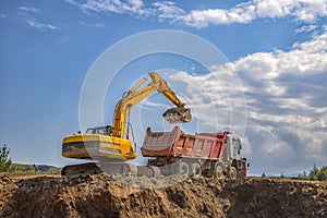 Yellow excavator and empty dump truck