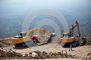 Yellow excavator is filling a dump truck with rocks at coal mines