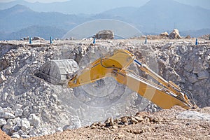 Yellow excavator is filling a dump truck with rocks at coal mines