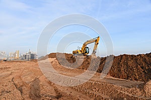 Yellow excavator during groundwork on construction site. Hydraulic backhoe on earthworks. Heavy equipment photo