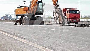 Yellow excavator with hydraulic hammer is building a highway