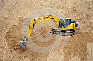Yellow excavator levels its bucket of sand, earth, clay. Construction of a sand embankment