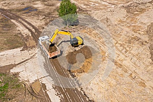 Yellow excavator loading a dump truck on construction site. aerial photo