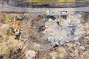 Yellow excavator loading dump truck at demolishing site. aerial view