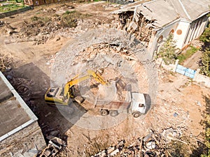 Yellow excavator loading out rubbish and debris into dump truck