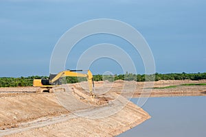 Yellow excavator machine working earth moving works riverside at construction site