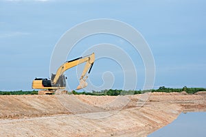 Yellow excavator machine working earth moving works riverside at construction site