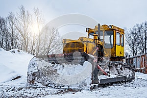 Yellow excavator on new construction site, with the bright sun and nice blue sky in the background. Yellow bulldozer in the winter