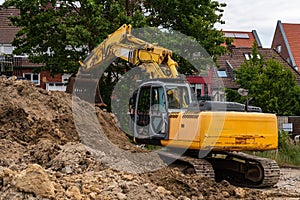 Yellow excavator piling up a pile of earth at a construction site