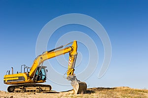 Yellow excavator under a clear blue sky