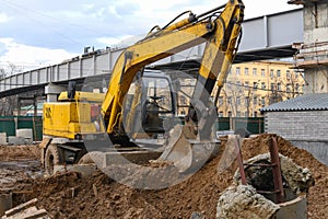 Yellow excavator on wheels digs the ground. Earthwork with an excavator