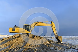 Yellow excavator working on construction site. The road construction