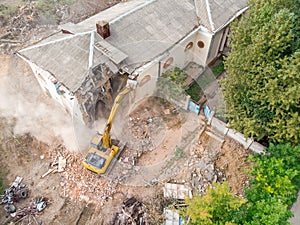 Yellow excavator working at old building destruction