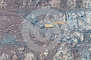 Yellow excavator working on the quarry, stone pit