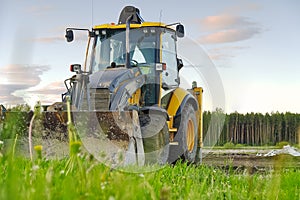 Yellow Excavator. yellow tractor on the field. Construction Machinery On Field. large yellow wheel loader aligns a piece