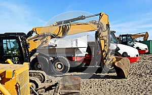 Yellow excavators and white dumping trucks lined up on the sand.