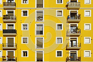 Yellow facade. Some aligned apartment windows making rows.