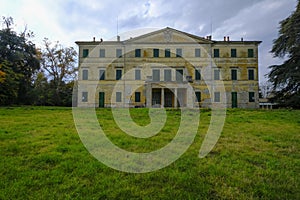 Yellow facade of the Villa Casino dei Boschi across the green meadow and dramatic sky. Boschi di Carrega, Emilia-Romagna, Italy photo