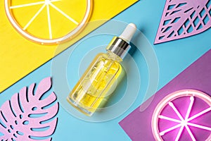 Yellow face oil in glass bottle with dropper on colorful geometric background photo