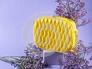 Yellow fashion lady handbag with purple flowers on monochrome background