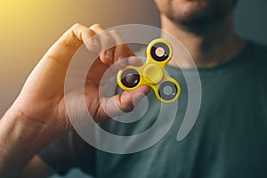 Yellow fidget spinner in male hand