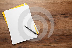 Yellow file, blank sheets of paper and pen on wooden table, top view. Space for text