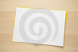 Yellow file with blank sheets of paper on wooden table, top view. Space for design