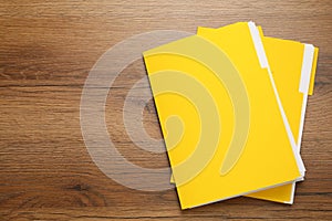 Yellow files with documents on wooden table, top view. Space for text