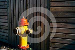 Yellow fire hydrant with red cap and silver lids, On a wooden background.