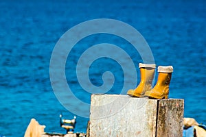 Yellow fishermens rubber boots on the sea shore