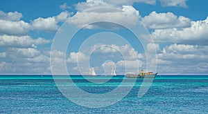 Yellow Fishing Boat and Two Sailboats on Aqua Sea