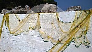 Yellow fishing net drying on the wall