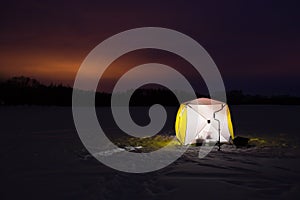 Yellow Fishing Tent On Ice Under Colorful Sky At Night Winter.