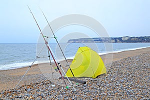 Yellow fishing tent on a pebble beach