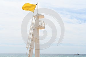 Yellow flag tower on a beach, indicating swimming caution