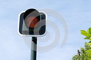 Yellow flashing orange traffic light signal for cars blue sky background